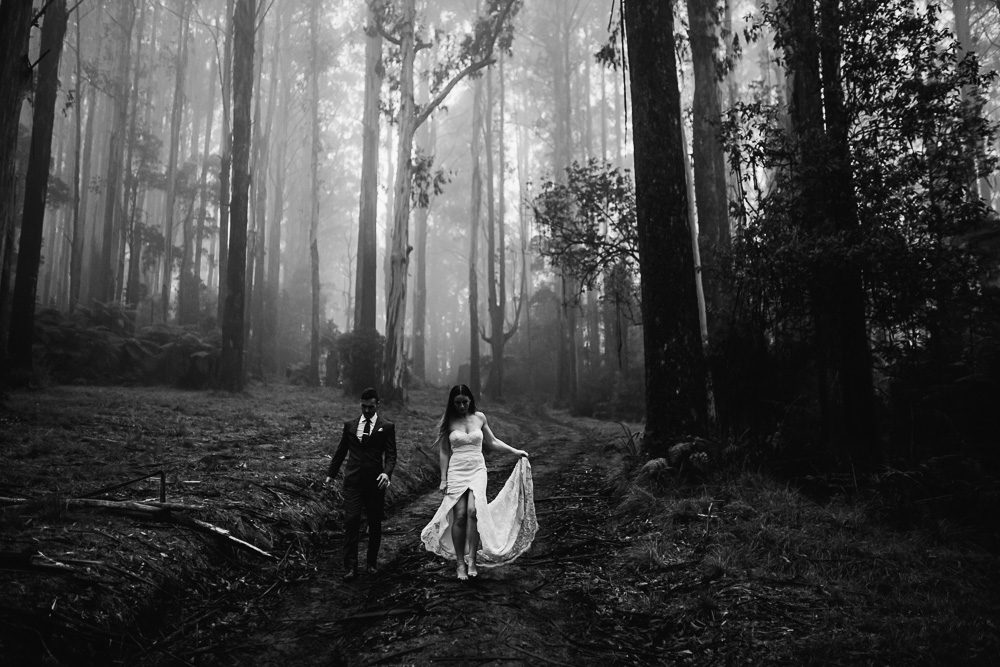 Black and white photo of wedding couple walking in the forest